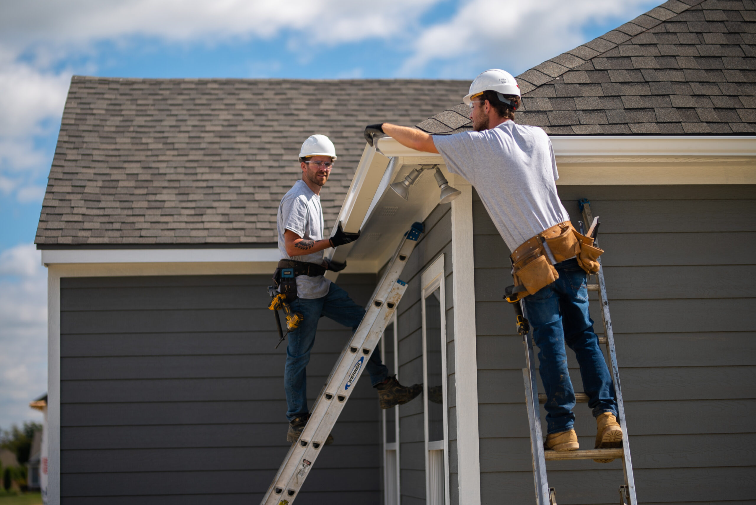 Seamless aluminum gutters being installed along the roof edge of a Miami home