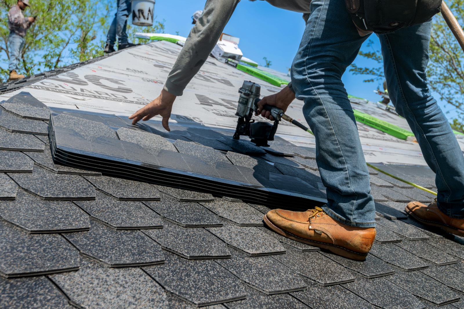 Professional roofer inspecting shingles during a roof repair versus replacement evaluation